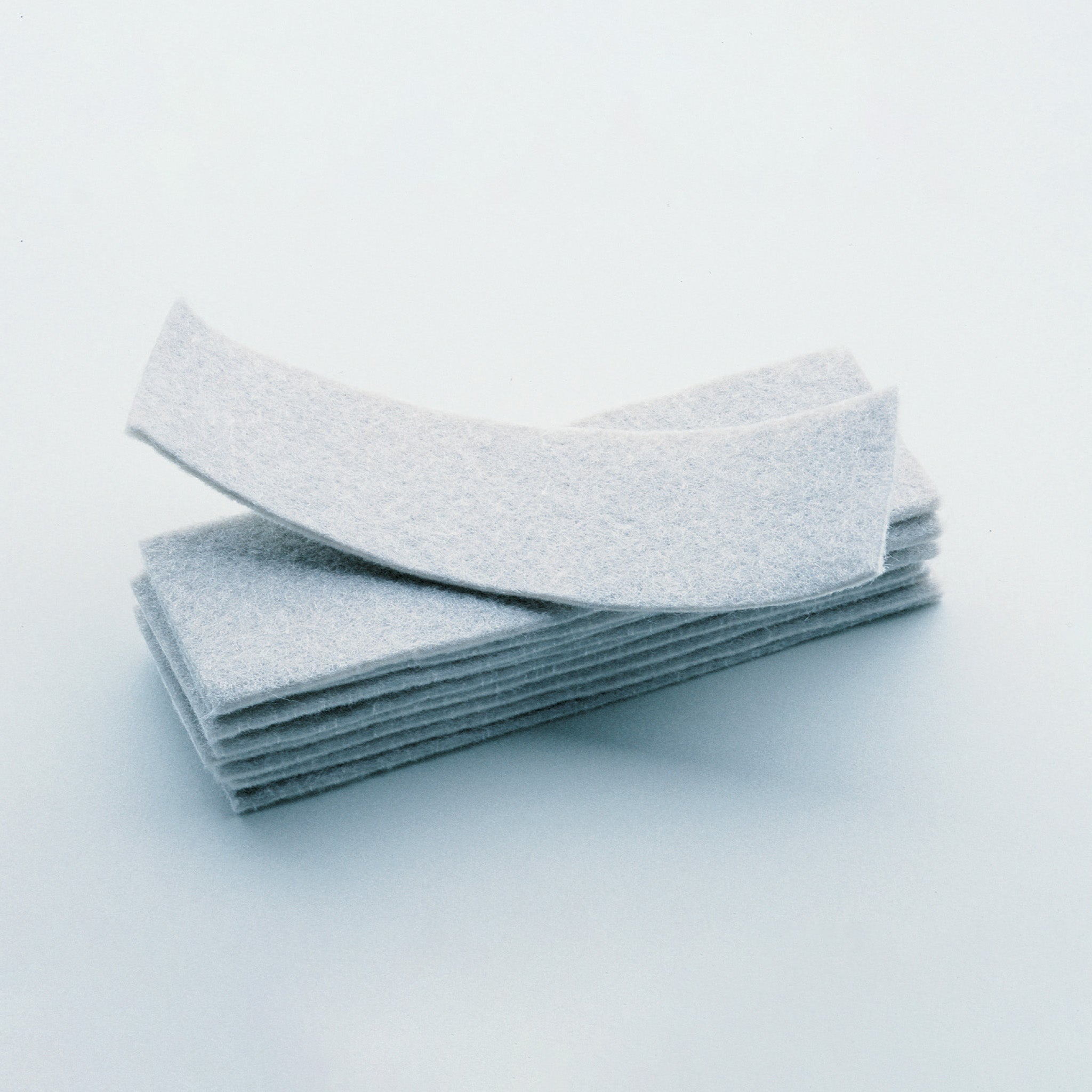 A stack of rectangular white Eraser pads for magnetic board eraser (10pcs) by Legamaster Shop, with one pad slightly curved and resting atop the others, displayed on a plain light background.